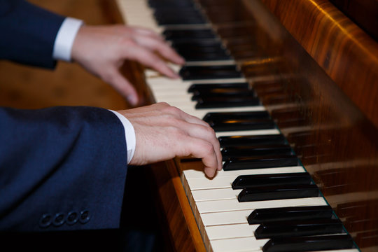 Pianist hands playing the piano. Classical music keyboard. Musician in concert performing music on a stringed percussive musical instruments.