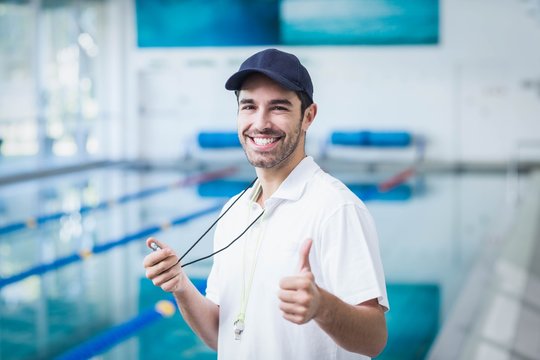 Happy trainer holding stopwatch with thumbs up