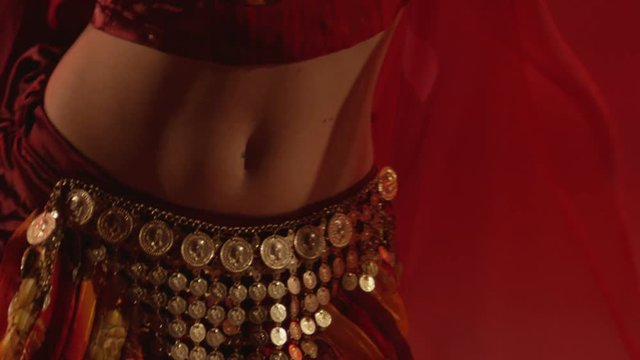 Beautiful traditional oriental belly dancer. Oriental girl dancing on red background. Studio shoot with fire. Shot on RED EPIC DRAGON Cinema Camera in slow motion.
