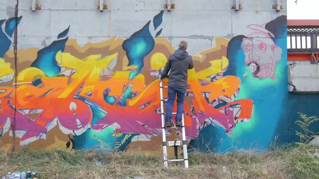 Graffiti artist painting on the wall, exterior