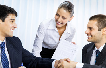 businesspeople handshaking with document