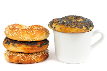 Stack of Poppy and sesame bagels with cup isolated