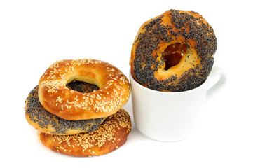 Stack of Poppy and sesame bagels with cup isolated