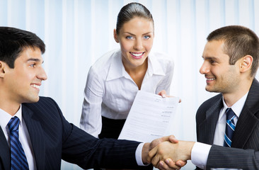 businesspeople handshaking with document