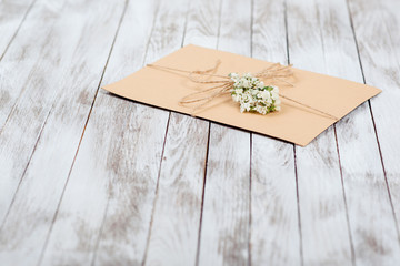 Greeting letter decorated with dry flowers on the wooden background.
