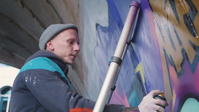 Graffiti artist painting on the wall, exterior