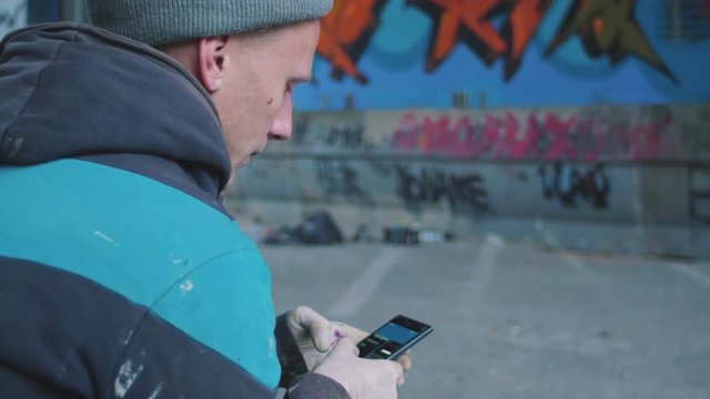 Graffiti artist using smartphone at graffiti background