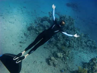 Rolgordijnen Beautiful freediver girl poses near the coral reef © serg269