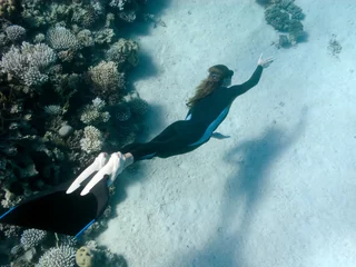 Foto op Canvas Beautiful girl with monofin swims near coral reef © serg269
