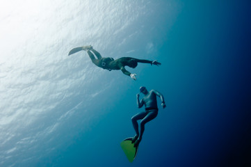 Fototapeta na wymiar Two freedivers have fun in the depth