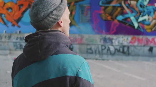 Graffiti artist smoking cigarette and watching at his work