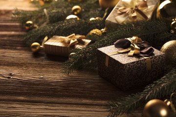 Golden Christmas decoration. Presents in boxes on a wooden background with copy space. Golden baubles. Christmas theme. Golden and brownish aesthetics. Christmas spices.