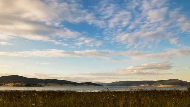 4K Tracking and tilting time lapse of a dam with a cloudy sky during a summer sunset.