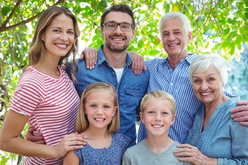 Smiling family standing against tree