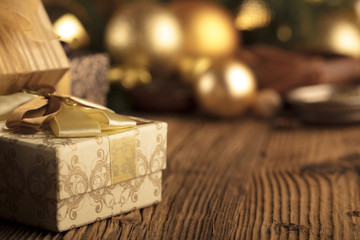 Naklejka na ściany i meble Golden Christmas decoration. Presents in boxes on a wooden background with copy space. Golden baubles. Christmas theme. Golden and brownish aesthetics. Christmas spices.