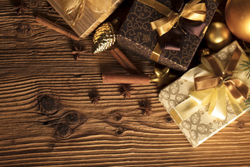 Golden Christmas decoration. Presents in boxes on a wooden background with copy space. Golden baubles. Christmas theme. Golden and brownish aesthetics. Christmas spices.