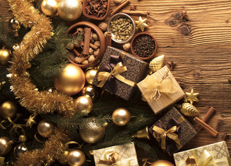 Golden Christmas decoration. Presents in boxes on a wooden background with copy space. Golden baubles. Christmas theme. Golden and brownish aesthetics. Christmas spices.