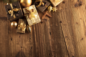 Golden Christmas decoration. Presents in boxes on a wooden background with copy space. Golden baubles. Christmas theme. Golden and brownish aesthetics. Christmas spices.