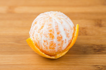 One navel orange peeled isolated on wood background
