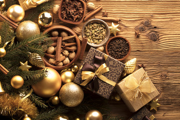 Golden Christmas decoration. Presents in boxes on a wooden background with copy space. Golden baubles. Christmas theme. Golden and brownish aesthetics. Christmas spices.