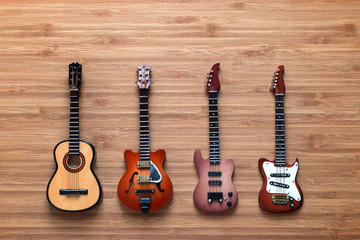 Set of four guitars on a wooden background.