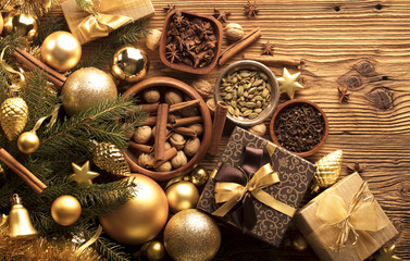 Christmas theme, christmas decoration. presents in boxes on a wooden table with golden baubles, clove, cardamon, star anise, cinnamon. Golden and brownish aesthetics. Place for typography and logo.
