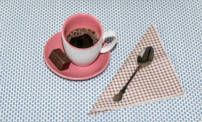 Cup of coffee and chocolate.Italy,November 11,2016 ,White cup and saucer, with a dark pink color in the inside,gently on a blue background,