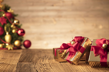 Golden presents with red ribbon under christmas tree. Wooden background and table. Red and gold. Place for typography and logo. Copy space. - Powered by Adobe