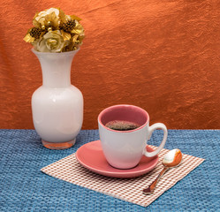 Cup of coffee .Italy,November 11,2016,White cup and saucer,color painting of the inner surface of a dark pink,cup of coffee on the coffee table, background blue and orange