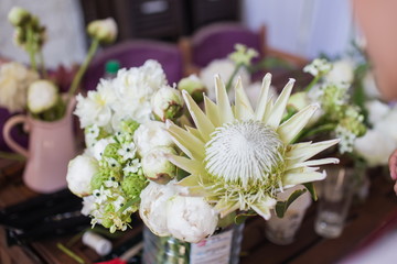 Beautiful white protea and David Austin roses on a table. Nice rare flowers for wedding decoration. Fresh bouquet for bride.