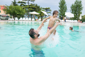 Young boy kid child splashing in swimming pool having fun leisur