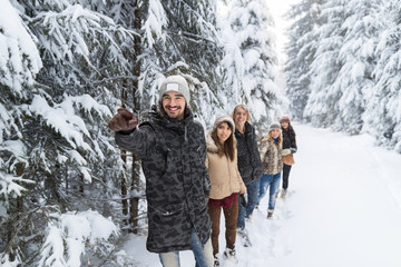 Fototapeta na wymiar Man Lead Friends Group Snow Forest Young People Walking Outdoor Winter Pine Woods