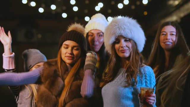 Group of attractive teen girls celebrating something outdoors. Female friends having fun, dancing in the street in winter. 60 FPS slow motion, 4K UHD RAW edited footage