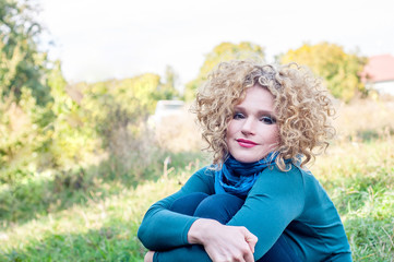 Cute curly blonde sitting on the grass