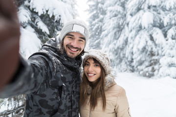 Fototapeta na wymiar Man Taking Selfie Photo Young Romantic Couple Smile Snow Forest Outdoor Winter Pine Woods