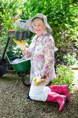 Cheerful senior woman holding potted plant in garden