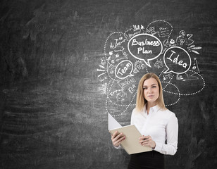Blond woman with a notebook near a chalkboard with business plan