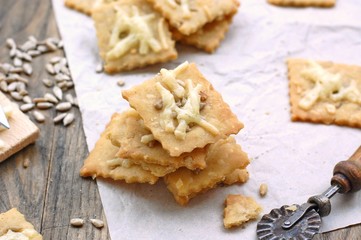 Homemade gluten free crackers with sunflower seeds and cheese on wooden background