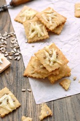 Homemade gluten free crackers with sunflower seeds and cheese on wooden background