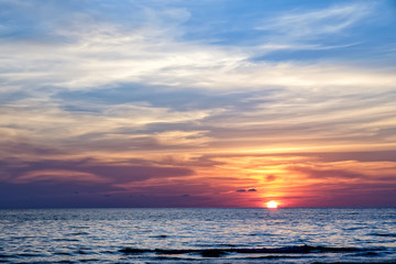 Coast of the sea at colorful sunset, Koh Chang, Thailand. Beach sunset is a golden sunset sky with a wave rolling to shore as the sun sets over the ocean horizon