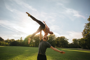 Fototapeta na wymiar Man and woman doing pair yoga outdoor in a park