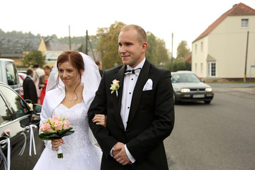 Młoda para przy samochodzie na drodze, ślub wesele.