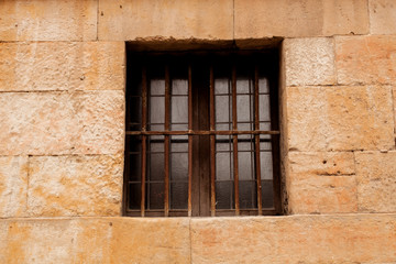 Fototapeta na wymiar Window with rusty grilles on a stone facade