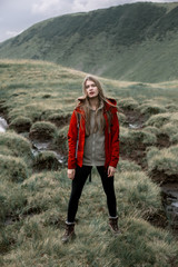 Shot of a young woman looking at the landscape while hiking in the mountains.Outdoor shot of attractive young woman with backpack standing in a mountain stream. Female hiker in creek water.