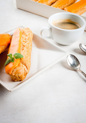 Eclairs with mango cream and  topping on a white wooden table. Drink tea or snack