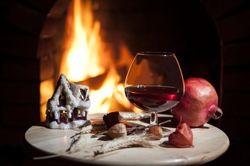 glass of brandy, candle,pomegranate, burning fireplace