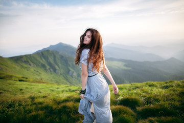 Young happy woman in long dress on the mountainside. Young girl in the mountains. Out of focus - 128212648