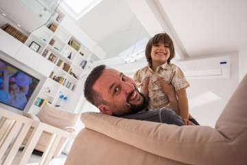 Cheerful young boy having fun with father on sofa