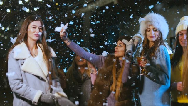 Group of attractive teen girls celebrating something outdoors. Female friends having fun, dancing in the snow. 60 FPS slow motion, 4K UHD RAW edited footage