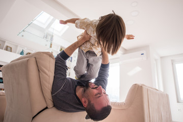 Cheerful young boy having fun with father on sofa